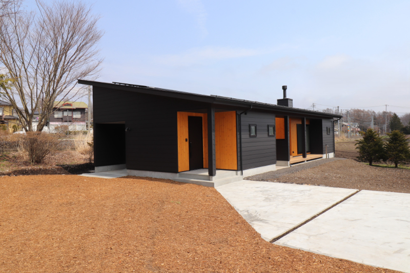 金属サイディングの黒い外壁と、木目がクールな外観の平屋